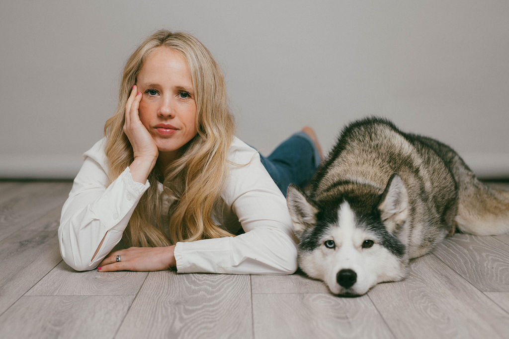 A woman and her husky lying side by side on the floor