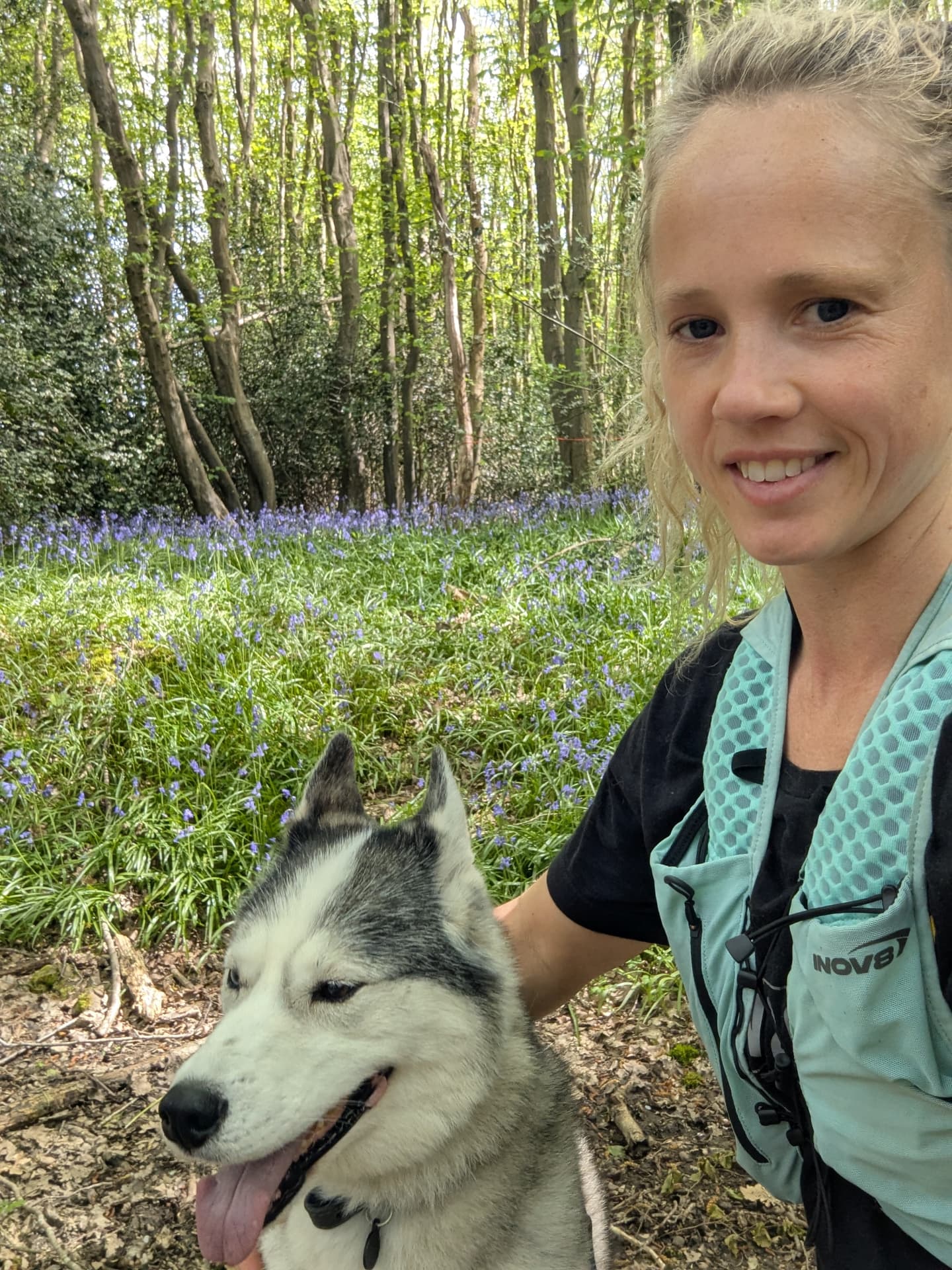 The Lone Wolf handler and her husky in a sunlit bluebell forest